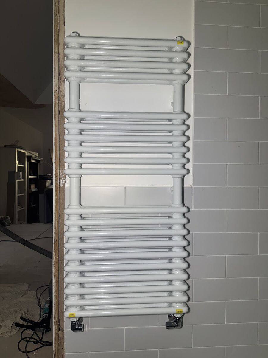 Heated towel rail fitted against a metro tile surround in a refitted bathroom