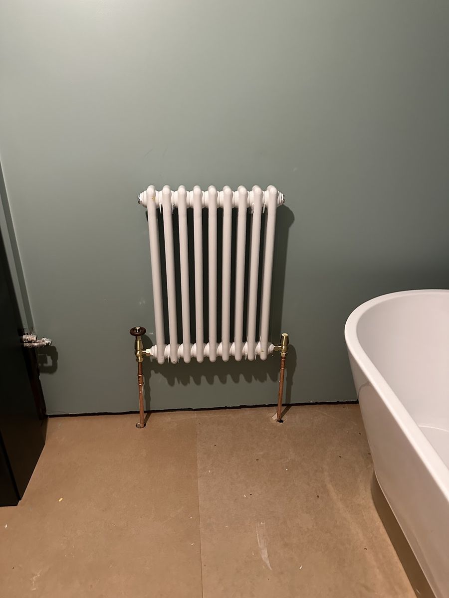 Traditional column radiator with brass valves fitted beside a freestanding bath, our own finished work